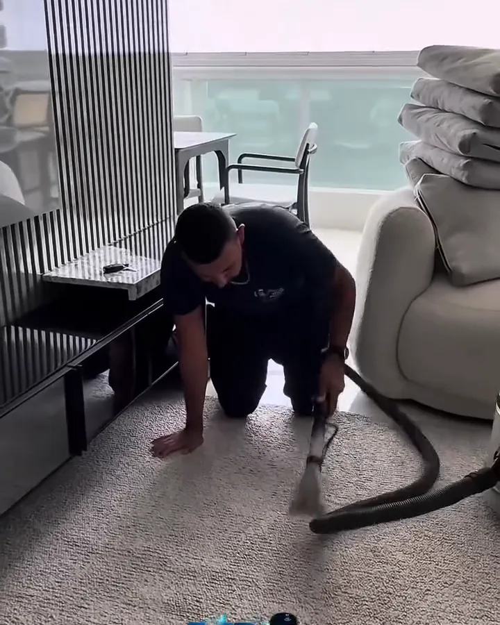 Vitor usando a máquina extratora em um tapete durante a higienização